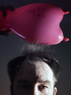 a man demonstrates static cling using his hair and a balloon.