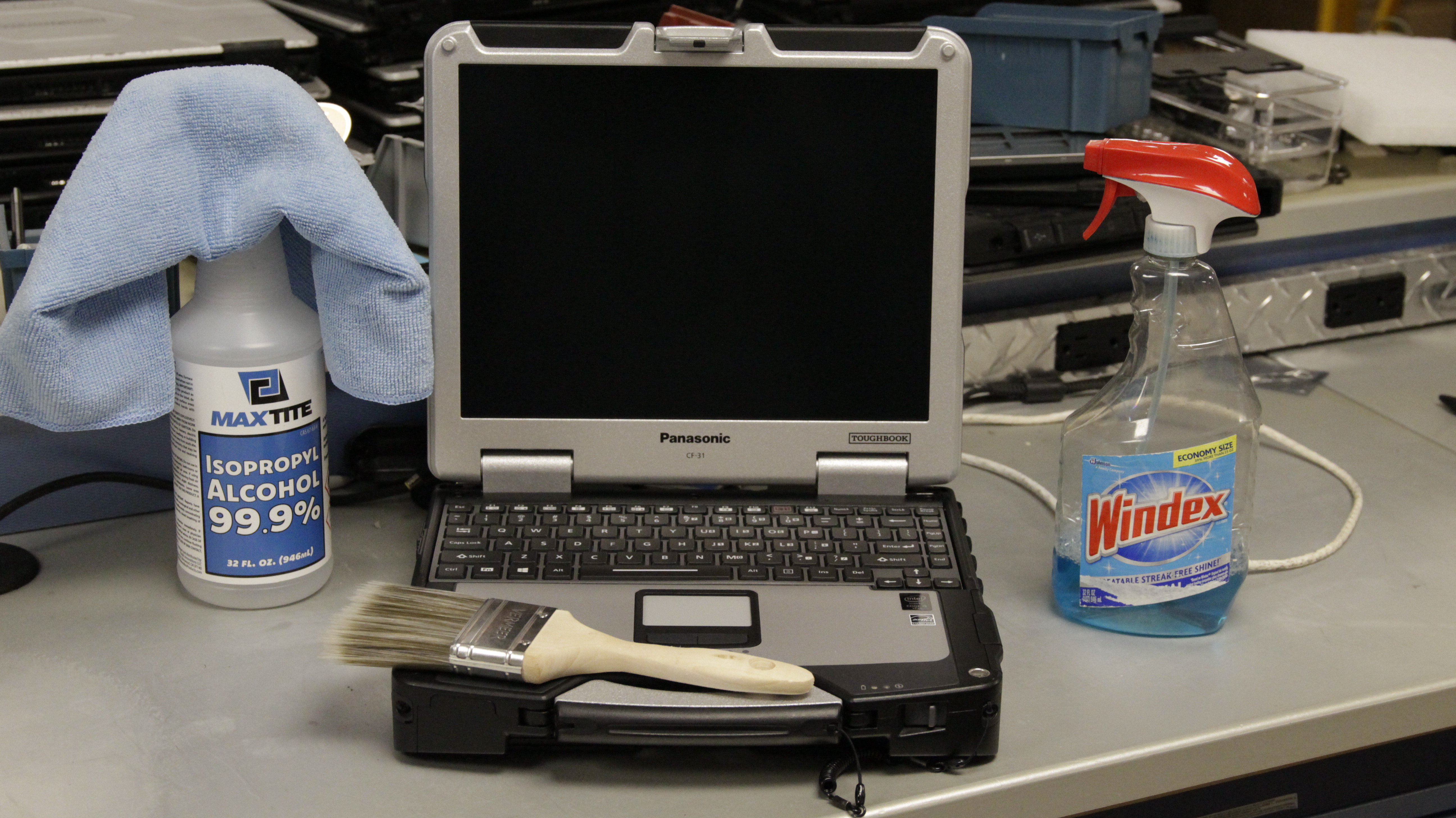 Some of the cleaning supplies used to clean our rugged laptops and tablets next to a Panasonic Toughbook CF-31
